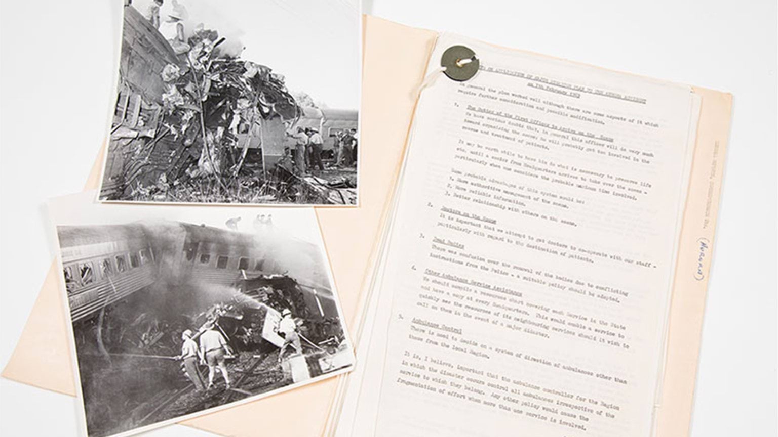 A folder with a typewriten report and several black and white photos of a train crash accident.