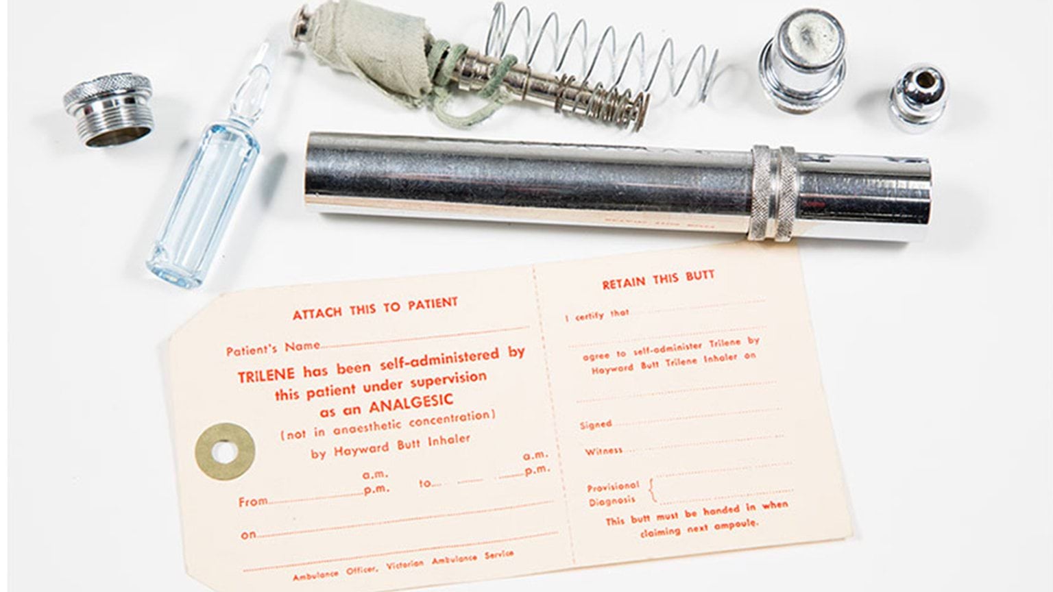 A metal tube accompanied by a piece of paper and a bottle.