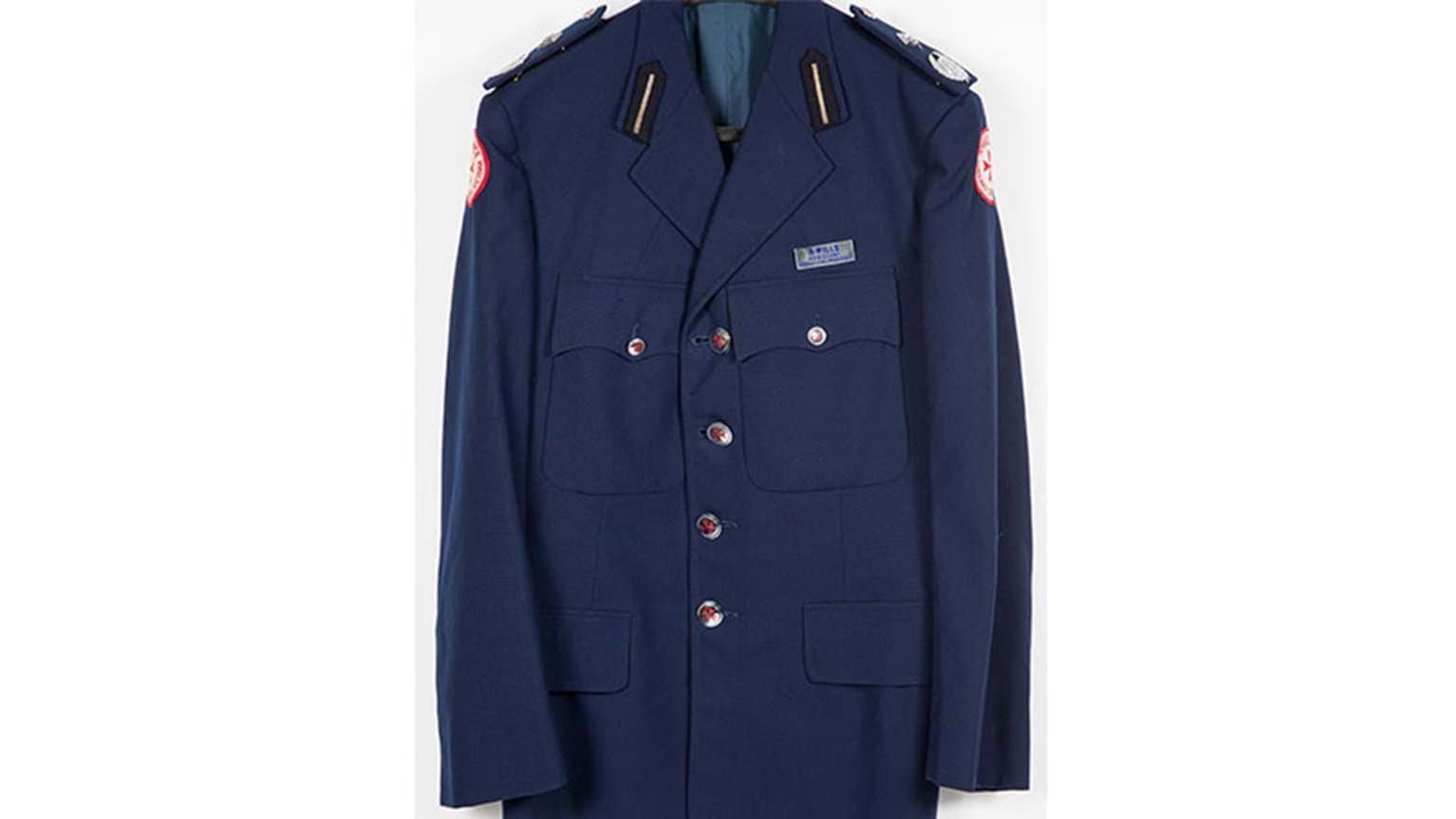 A blue coat featuring gold-red buttons and and a name tag above the front pocket.