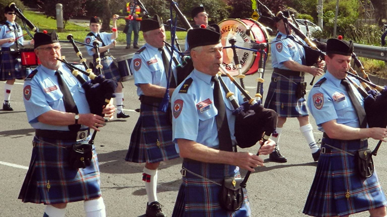 Band members blowing bagpipes as they march down the street. Band members blowing bagpipes as they march down the street.