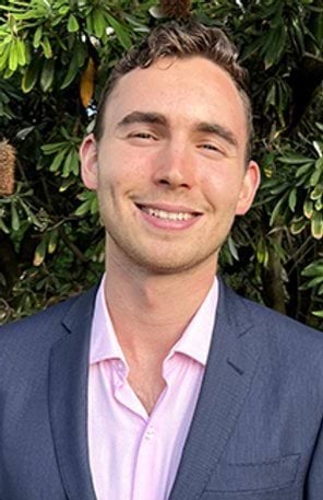 A man in a shirt and suit jacket smiles at the camera