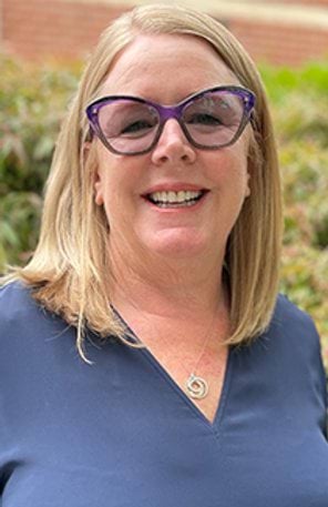 A woman wearing glasses and smiling at the camera