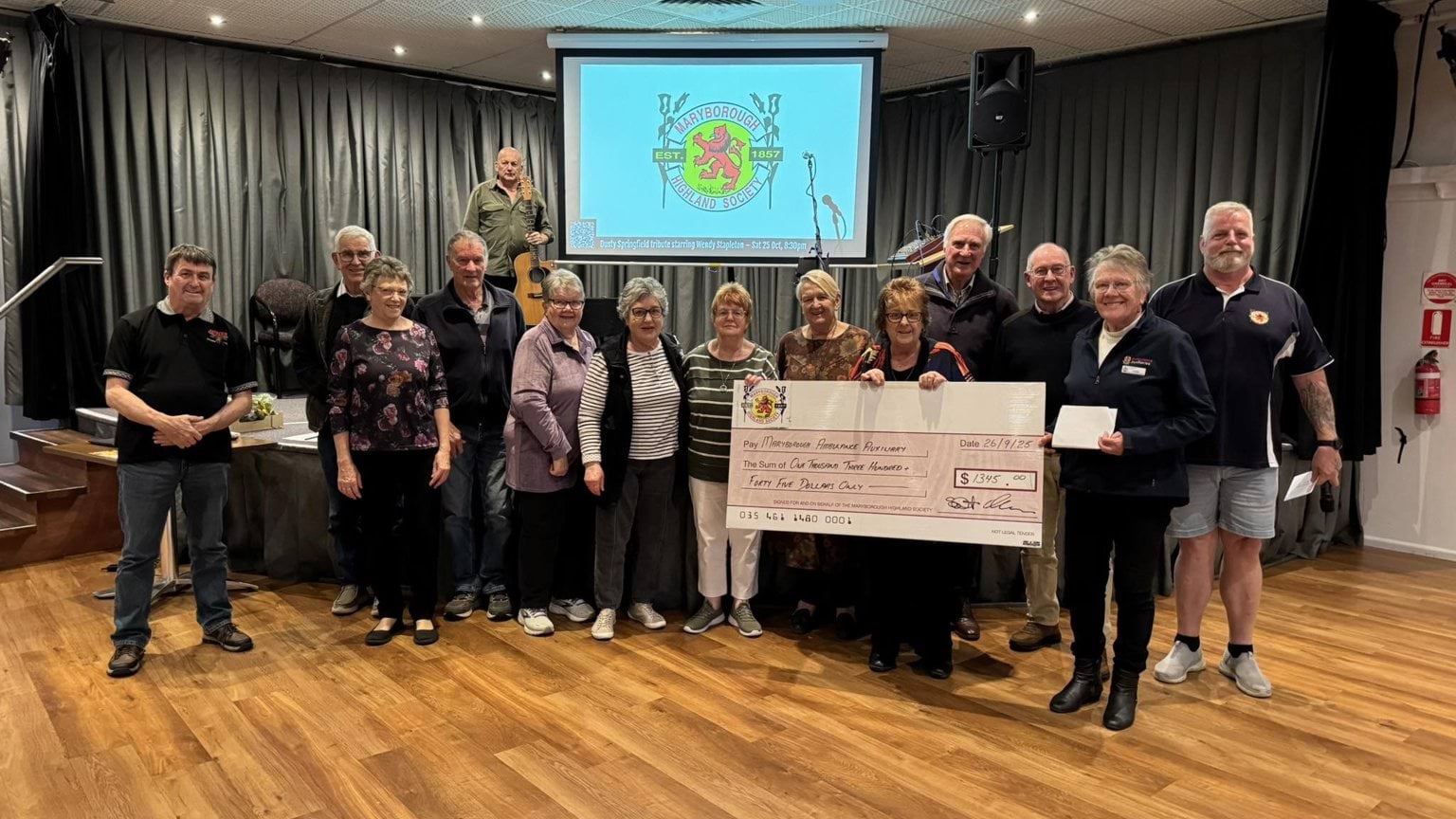 A large group of people holding a large cardboard bank cheque.