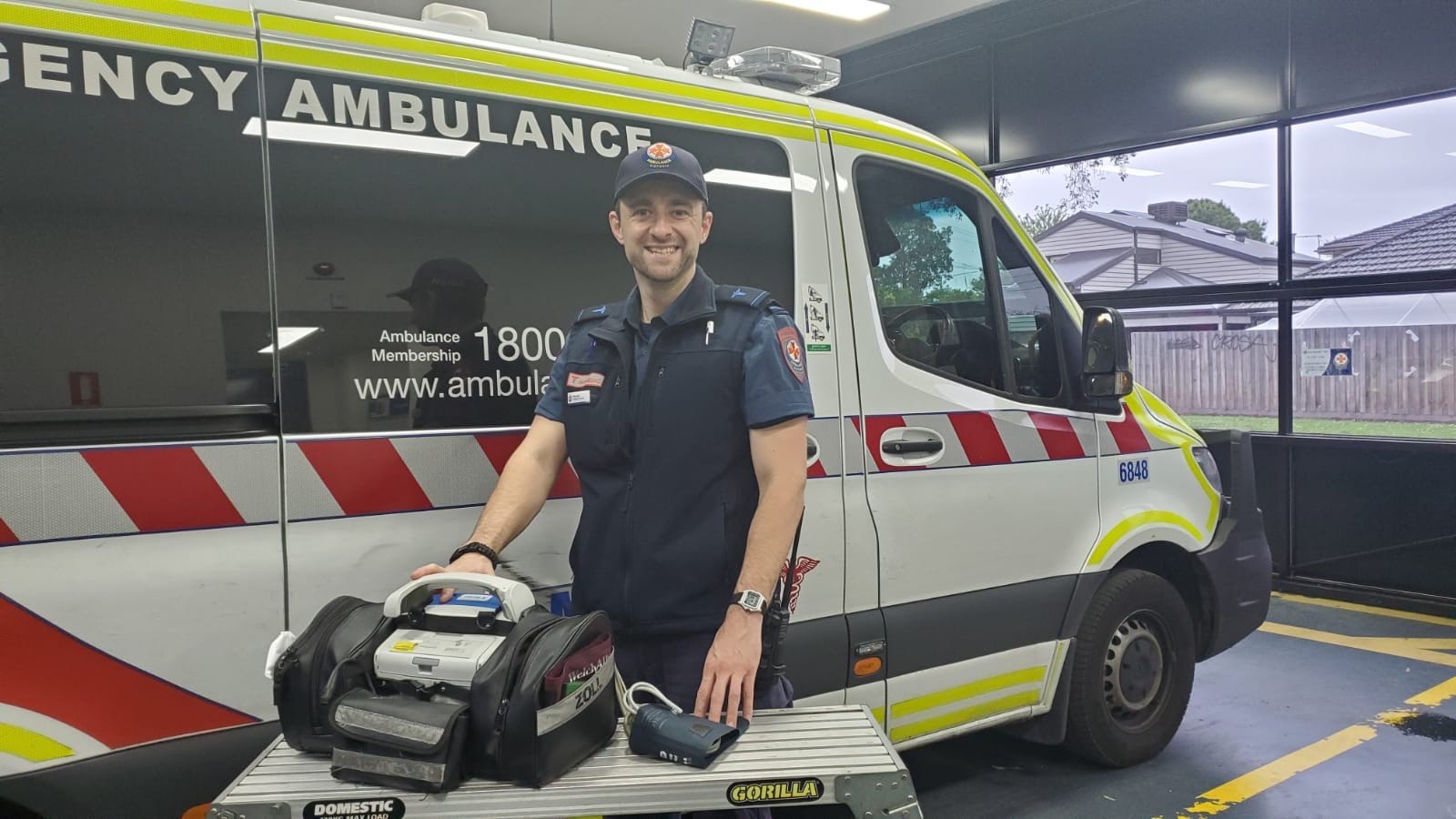 An Ambulance Victoria paramedic smiles in front of an ambulance.