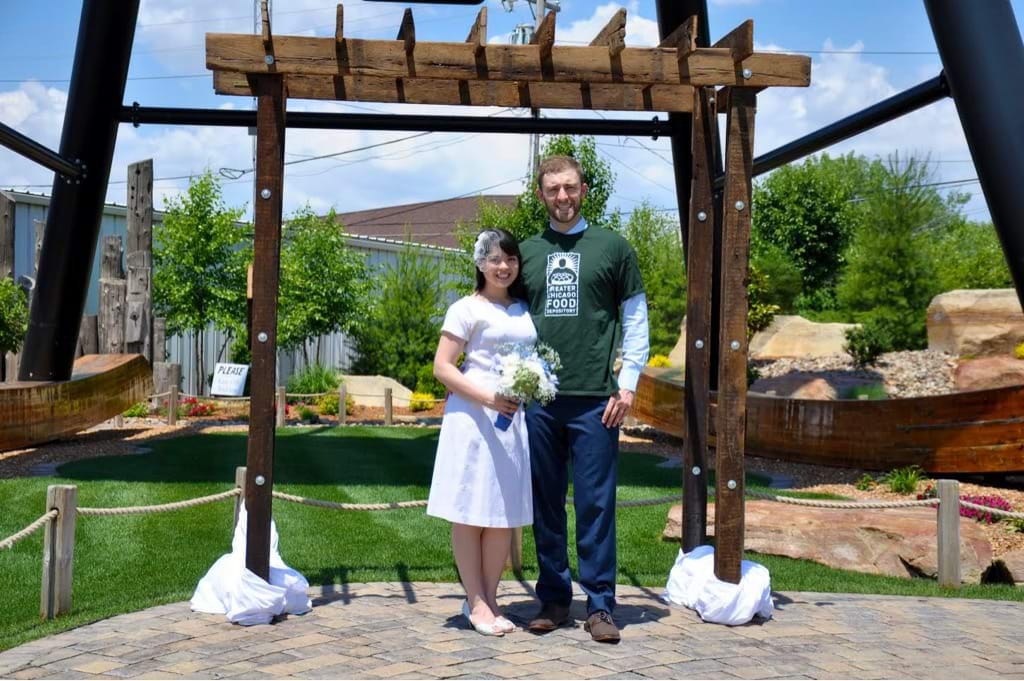 A woman in a wedding dress and a man in a Foodbank t-shirt smile for the camera.