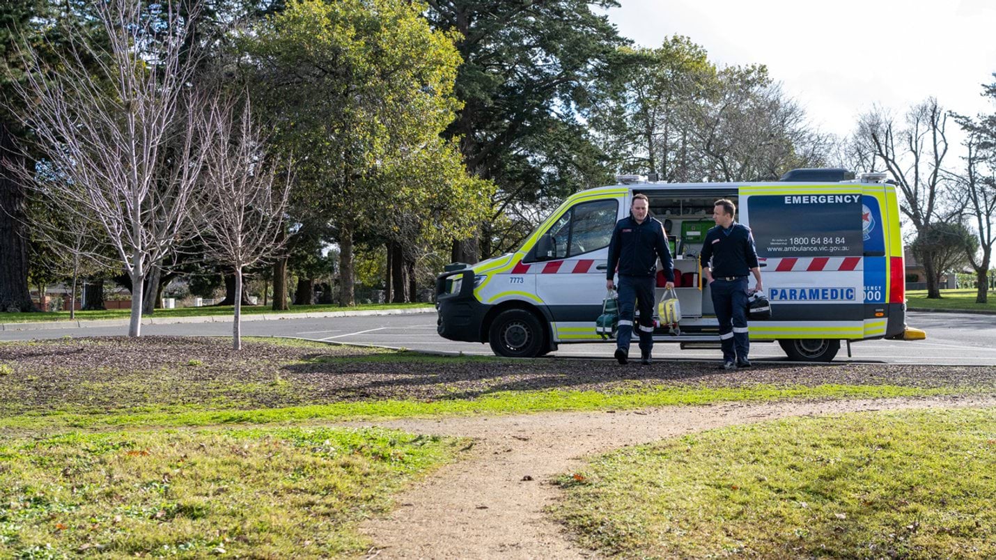 Two paramedics with their equipment beside an ambulance