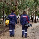 Two paramedics carry walk along a path in the bush