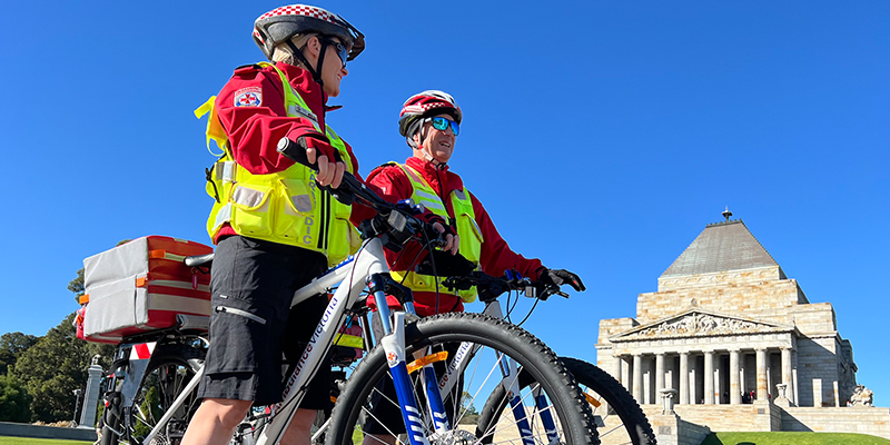 Two bicycle paramedics are on their bicycle in front of the Shrine of Remembrance.