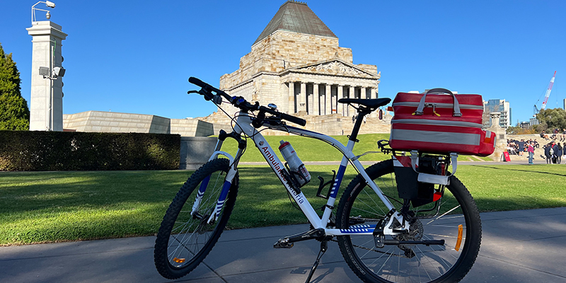 An Ambulance Victoria bicycle equipped with medical gear and in front of the Shrine of Remembrance.