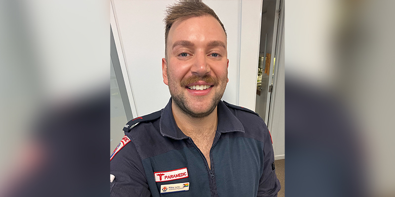 A male paramedic smiling in a profile shot.