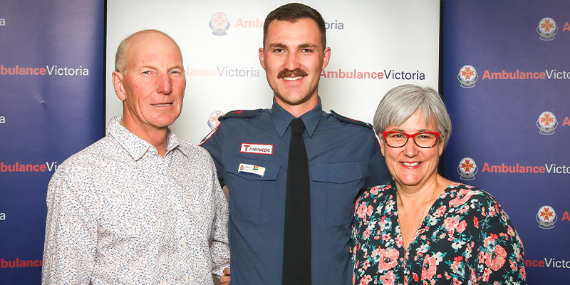 A paramedic standing proudly with his parents.