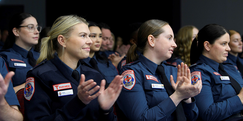 A groups of graduate paramedics clapping their hands at the graduation ceremony.