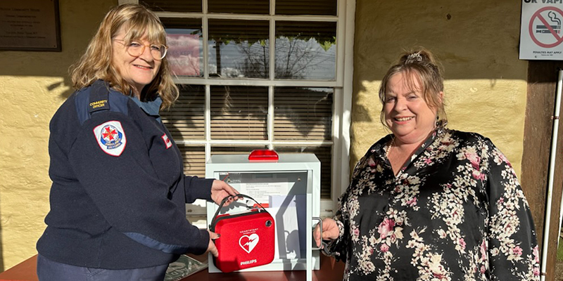 An Ambulance Community Officer is showcasing the new automated external defibrillator device that is being installed at the Community House in Heathcote. 