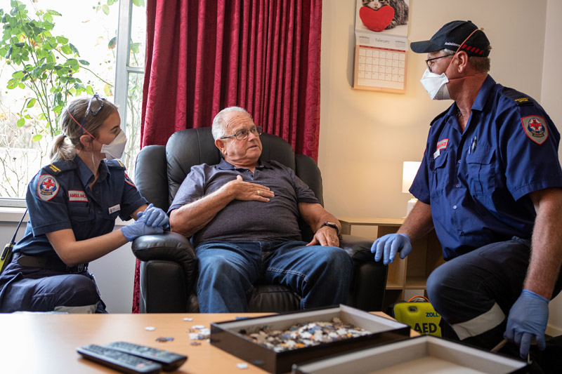 Two paramedics attend to a man in his home