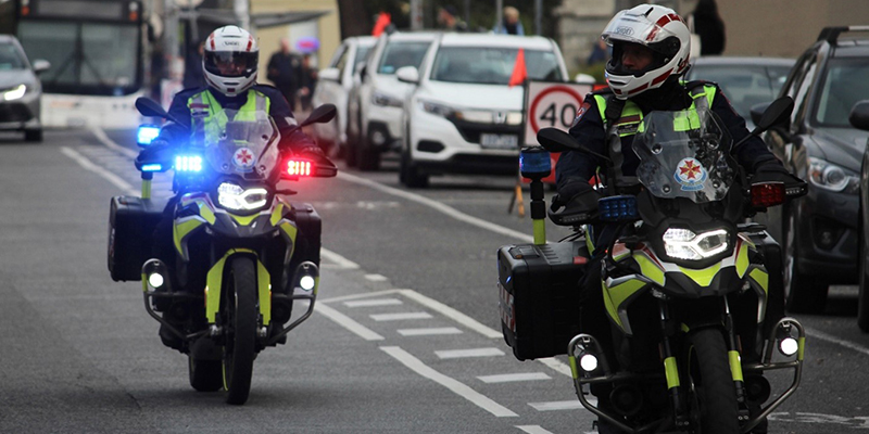 Two paramedics riding motorcycles on a busy street, patrolling the area with focused determination.