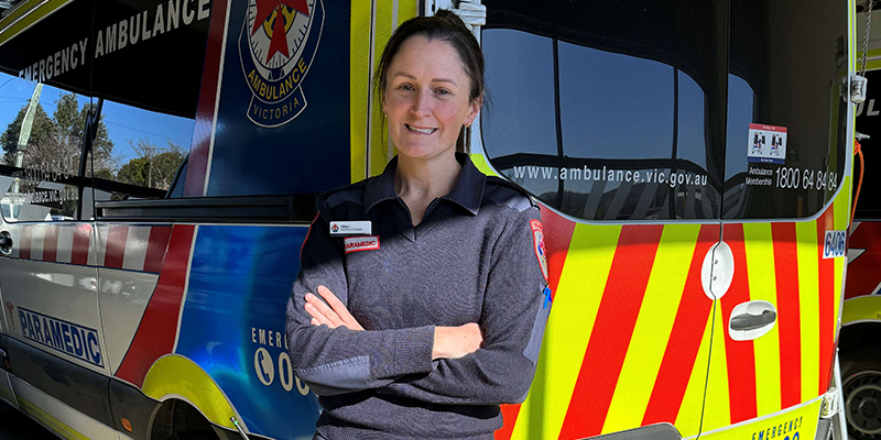 A female paramedic standing next to ambulance.