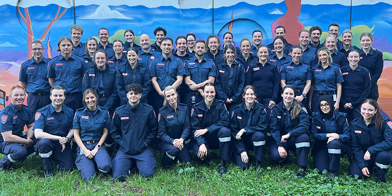 A diverse group of paramedics in uniform smiling for a picture.