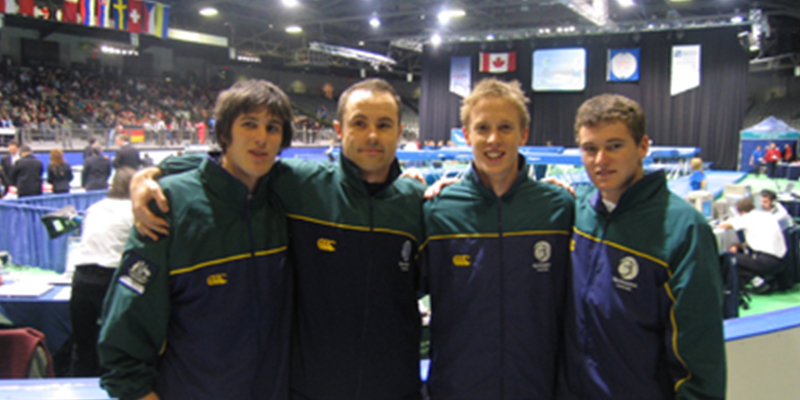 Four athletes standing together shoulder-to-shoulder at a sporting event.