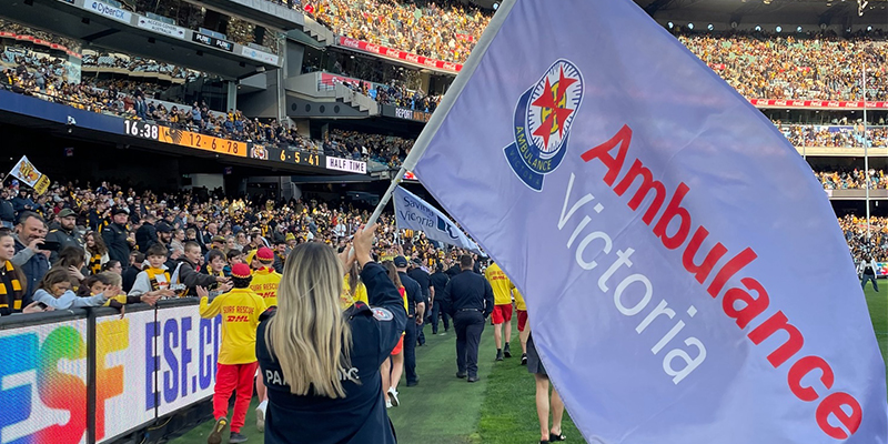 A woman proudly holds a flag while cheering at a lively football game, showcasing her team spirit and enthusiasm.