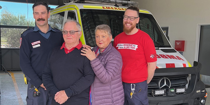 Four people are standing in front of an ambulance.