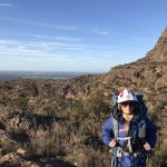 A woman paramedic in wilderness response uniform standing in a bush landscape.