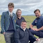 Four people posed at a picnic table, smiling for the camera.