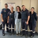 A group of four paramedics standing with a patient.