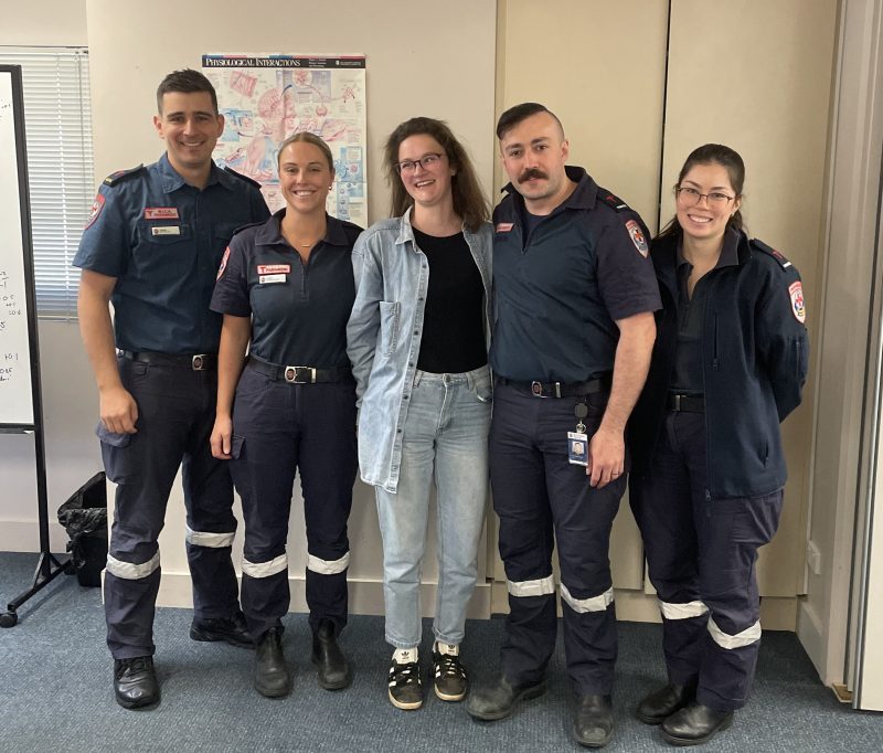 A group of four paramedics standing with a patient. 