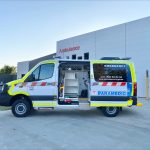 An all-wheel-drive ambulance vehicle with the side door open, parked in front of an Ambulance Victoria branch.