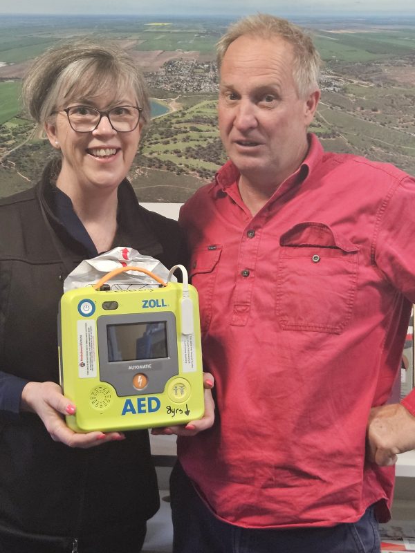 A man and a woman holding an AED.