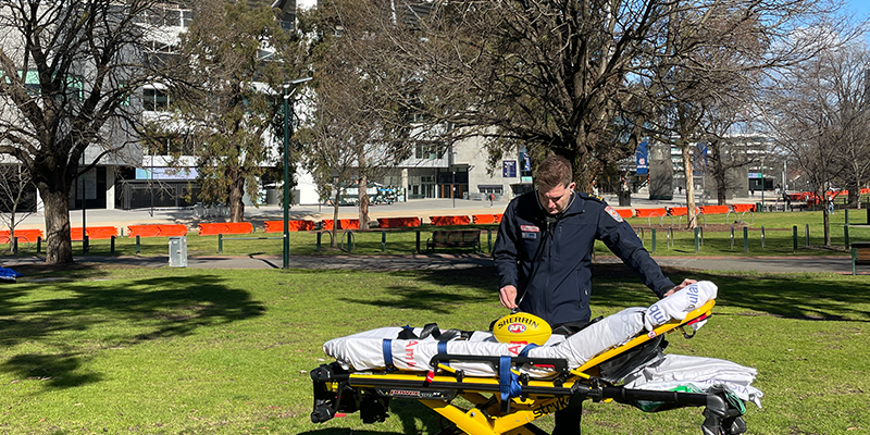 A paramedic placing a football on a stretcher bed outside the stadium.