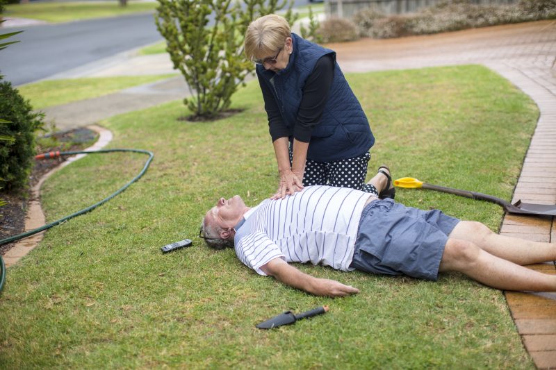 Woman performs CPR on a man unconscious in the garden.