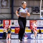 A woman referee runs down a basketball court.