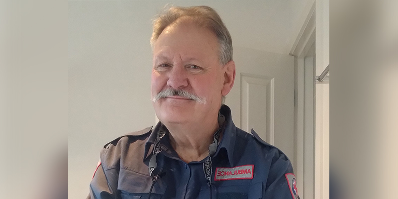 A man standing in a white room with an opened door and smiling for the camera.