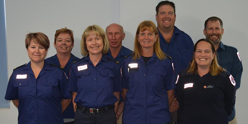 Eight ambulance staff standing together in a white room.