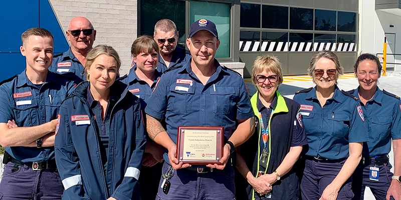 A diverse group of uniformed individuals proudly holding a prestigious award, showcasing teamwork and achievement