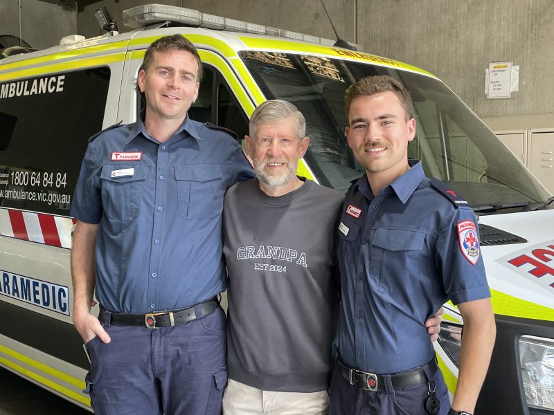 Three men standing in front of an ambulance.