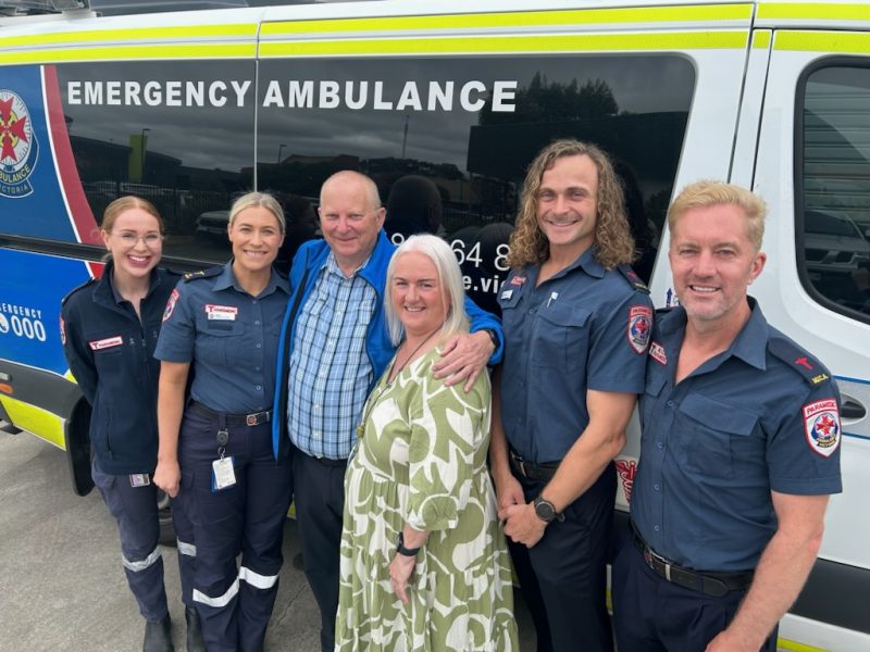 A group of people standing in front of an ambulance.