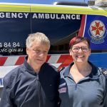 A man and woman standing in front of an ambulance.