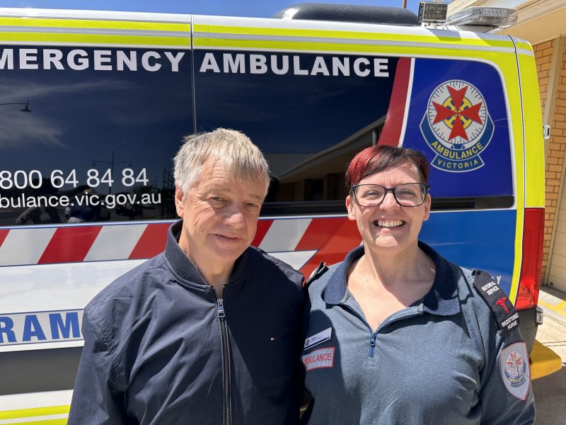 A man and woman standing in front of an ambulance.