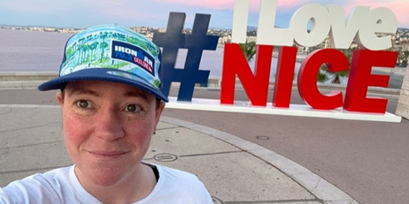 A woman wearing a cap and standing in front of a 'I Love Nice' signage.