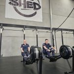 A man and woman in Ambulance Victoria paramedic uniform sit on rowing machines in The Shed Gym.