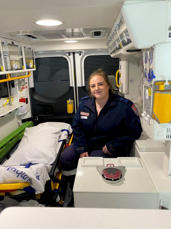 A woman paramedic smiles for the camera inside an ambulance.