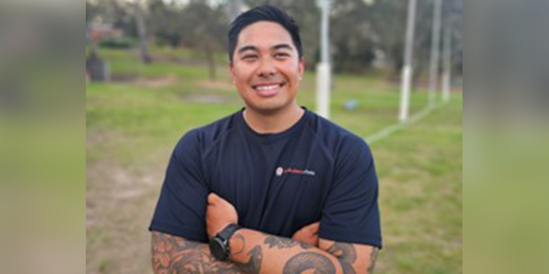 A man standing on a field with his arms folded across his chest. 