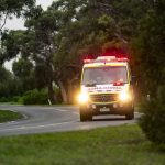 Ambulance driving with headlights and beacons on.