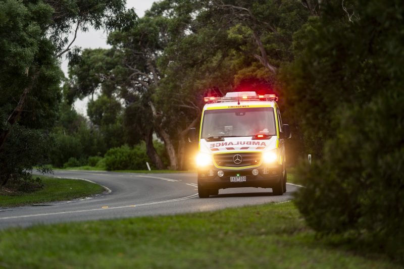 Ambulance driving with headlights and beacons on.