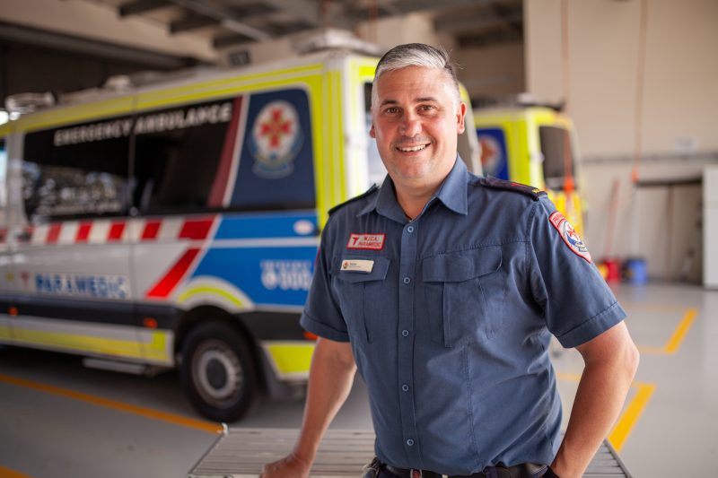 A male paramedic standing in front of an ambulance.