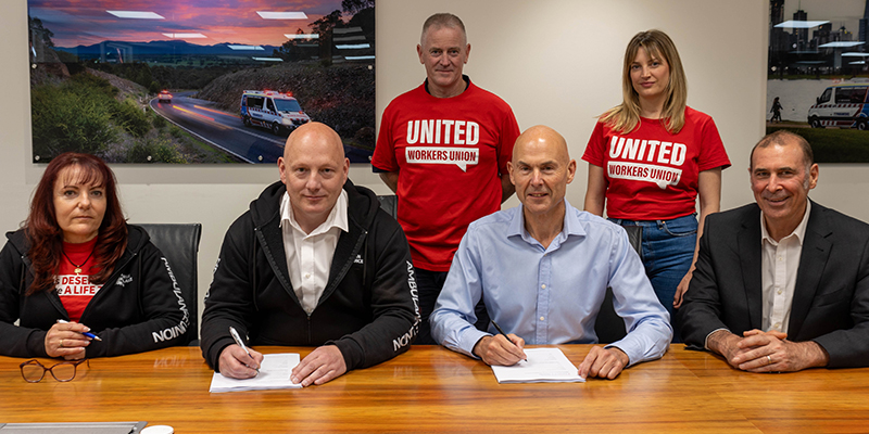 A group of people signing agreement documents on a table.