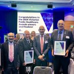 Five men and one woman smile for the camera at the Victorian Public Healthcare Awards event. Three of the men hold certificates.