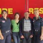 Four people in front of a fire truck.